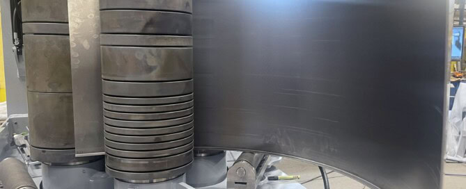 SweBend SB3-105 CNC section bending machine with flanged plate loaded between profiled rolls and hydraulic guide rolls